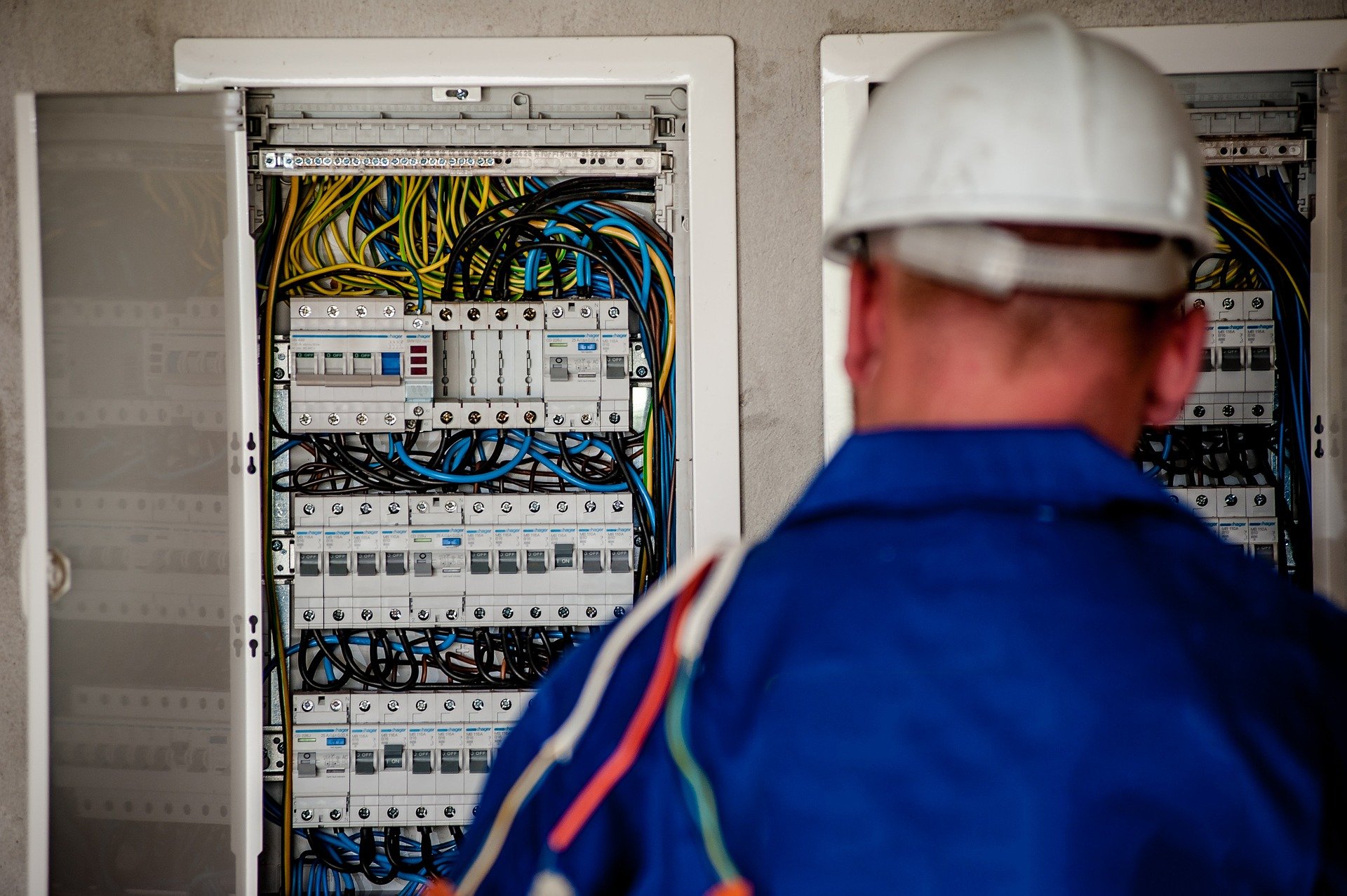 Electricista trabajando ante un cuadro eléctrico abierto